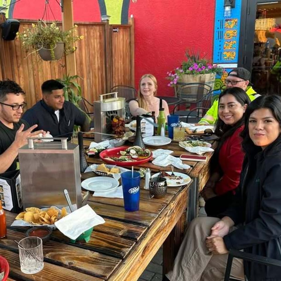 Group of friends enjoying tacos and drinks at a vibrant outdoor patio at Tacos El Rey.